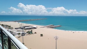 A beach with a clear view of the ocean, a sandy shore, and a city skyline in the distance.