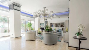 A spacious lobby with a chandelier, seating areas, and potted plants. - Beachfront Studio  overlooking the Atlantic Ocean (Fort Lauderdale Beach)