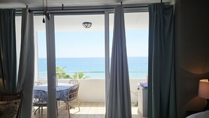 A room with a bed, a table with chairs, and a view of the sea through a sliding glass door. - Beachfront Studio  overlooking the Atlantic Ocean (Fort Lauderdale Beach)