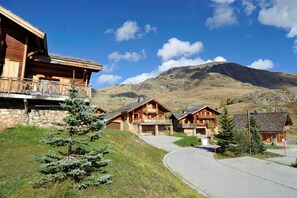 Un rifugio alpino con chalet in legno, pareti in pietra e vista chiara sulle montagne circostanti.
