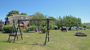 En park med en gunga, en båt och en byggnad med halmtak.