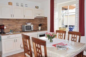 Une cuisine avec des meubles blancs, un four à micro-ondes et une table à manger avec des chaises.