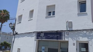 A white building with multiple windows, a ground-floor entrance, and a sign for 'CORREDOR DE SEGUROS RAMOS ROMAN.' - Terrace with Breathtaking Views - Apartment Sebastian (conil de la frontera)