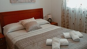 A neatly made bed with a quilted bedspread, pillows, and rolled towels. - Terrace with Breathtaking Views - Apartment Sebastian (conil de la frontera)