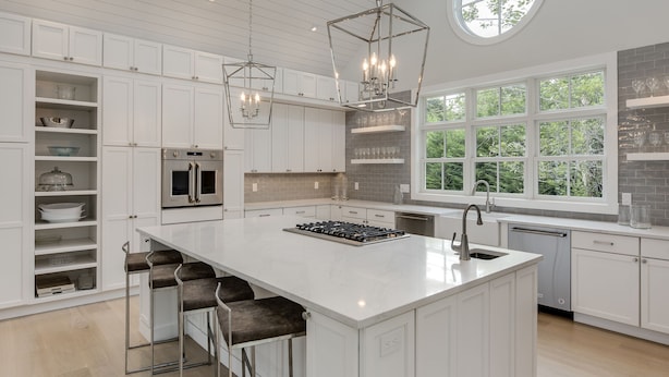 A modern kitchen with white cabinetry, a large island, and a hanging light fixture. - Stunning Hampton Holiday Family Fantasy for your Team  (East Hampton)