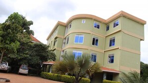 A multi-story building with a curved facade, several windows, and a paved driveway. - Golden Peace Hotel (Gulu)