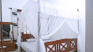 A bedroom with a wooden bed, white bedding, and a canopy.