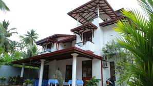 A two-story house with a covered patio, white walls, and a red roof.