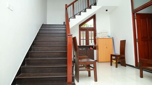 A staircase with wooden steps and a wooden handrail, leading to a room with a wooden door and a window.