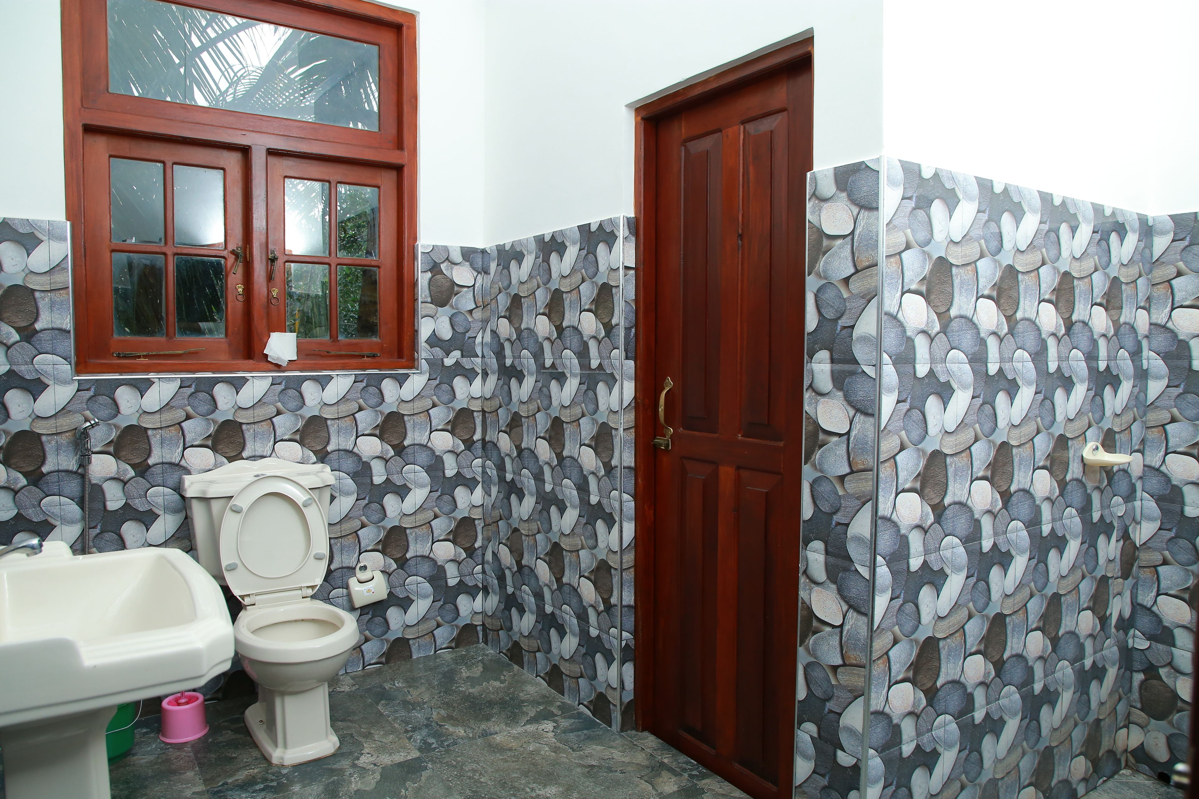 A bathroom with a toilet, sink, and a wooden door.