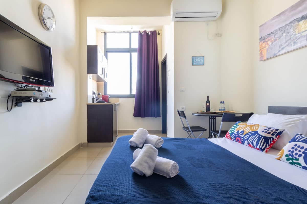 Une chambre d’hôtel avec un lit, une télévision, un bureau et une fenêtre avec des rideaux.