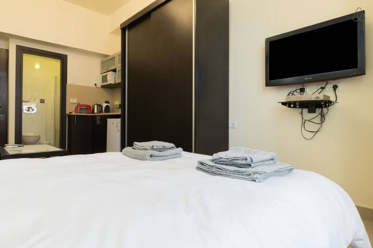 Une chambre d’hôtel équipée d’un lit, d’un téléviseur fixé au mur, d’un four à micro-ondes et d’une petite kitchenette.