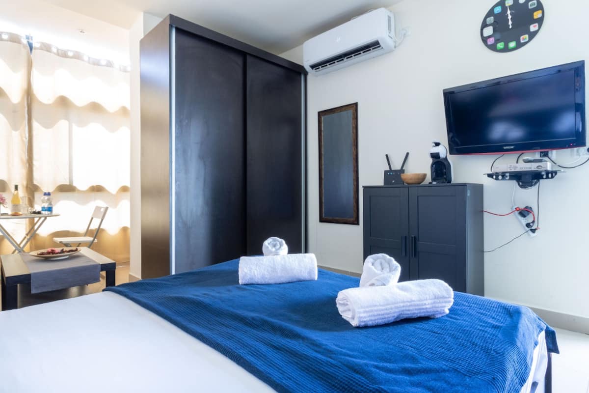 Une chambre d’hôtel comprenant un lit, un bureau avec une chaise, une armoire, un téléviseur et un appareil de climatisation.