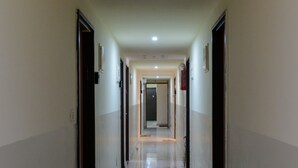 A long, narrow hallway with doors on both sides, a welcome mat at the entrance, and a light-colored floor. - NHE Rothschild Apartments (Tel Aviv)