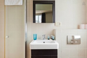 A bathroom with a white sink, a mirror, and a towel hanging on the door.