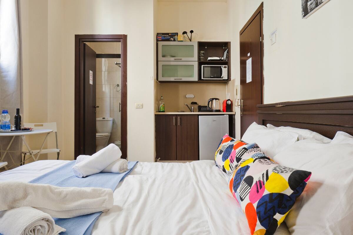 Une chambre d’hôtel équipée d’un lit, d’un petit bureau avec une chaise, d’un four à micro-ondes et d’une machine à café.