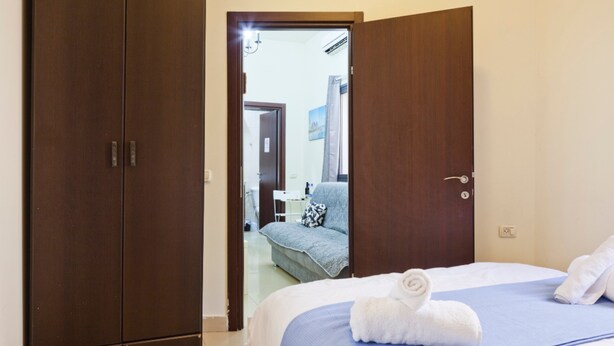 Une chambre d’hôtel avec un lit, une armoire et une salle de bain, visibles à travers une porte ouverte.