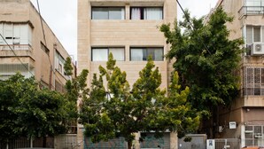 Un immeuble de taille moyenne, doté d’une façade simple et rectangulaire, de nombreuses fenêtres et d’un balcon au deuxième étage.