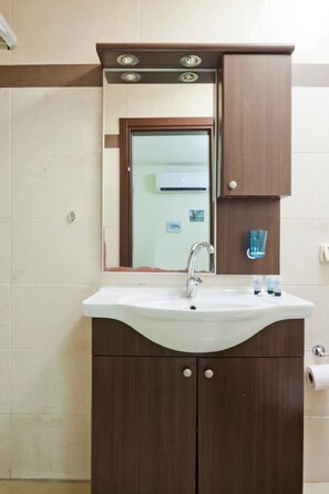 A bathroom with a white sink, a mirror, and a wooden cabinet.