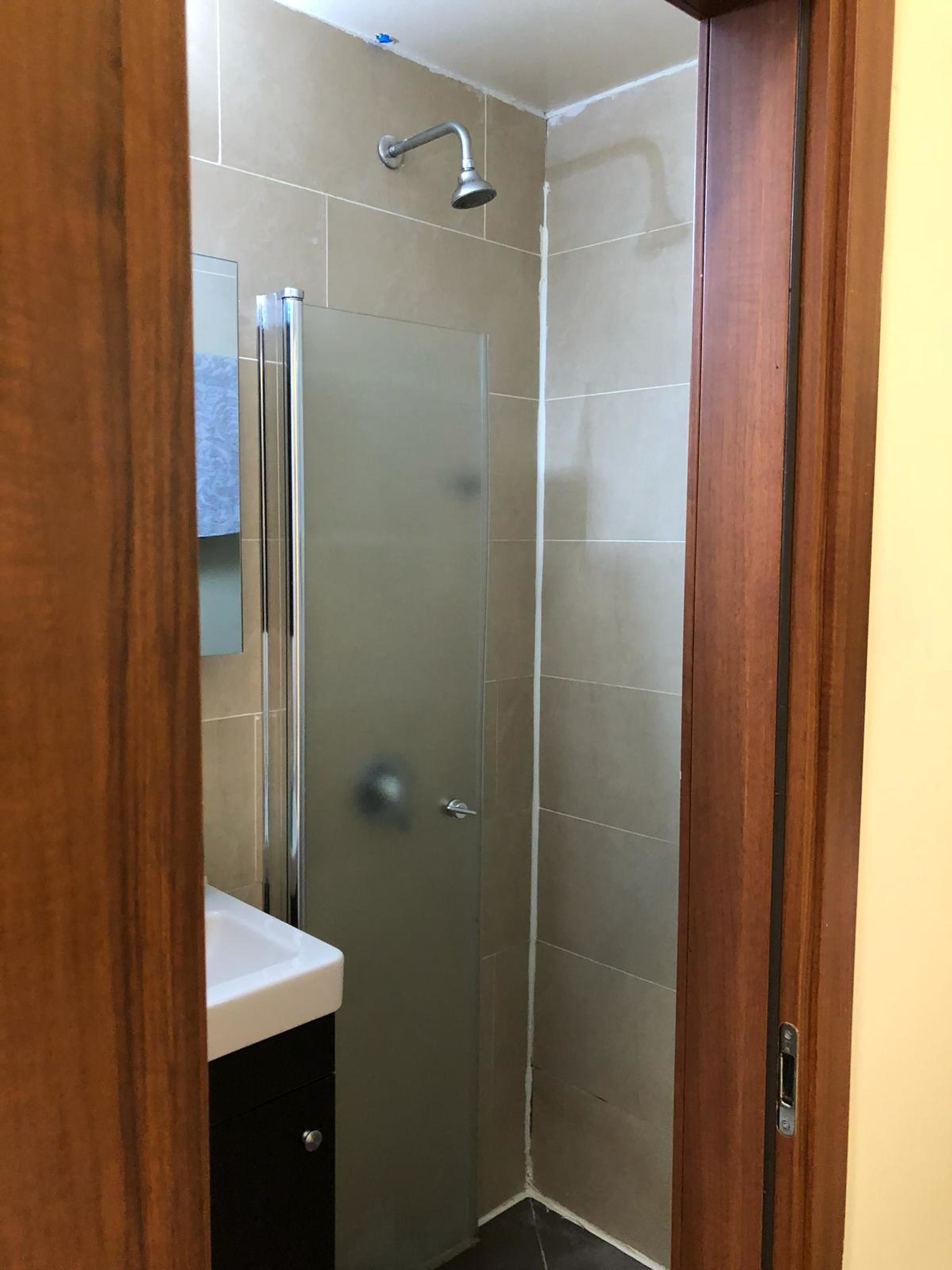 A bathroom with a shower, a mirror, and a sink.