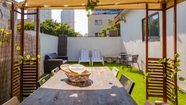 A covered patio with a wooden table, chairs, and a grill. - NHE Rothschild Allenby Apartments (Tel Aviv)