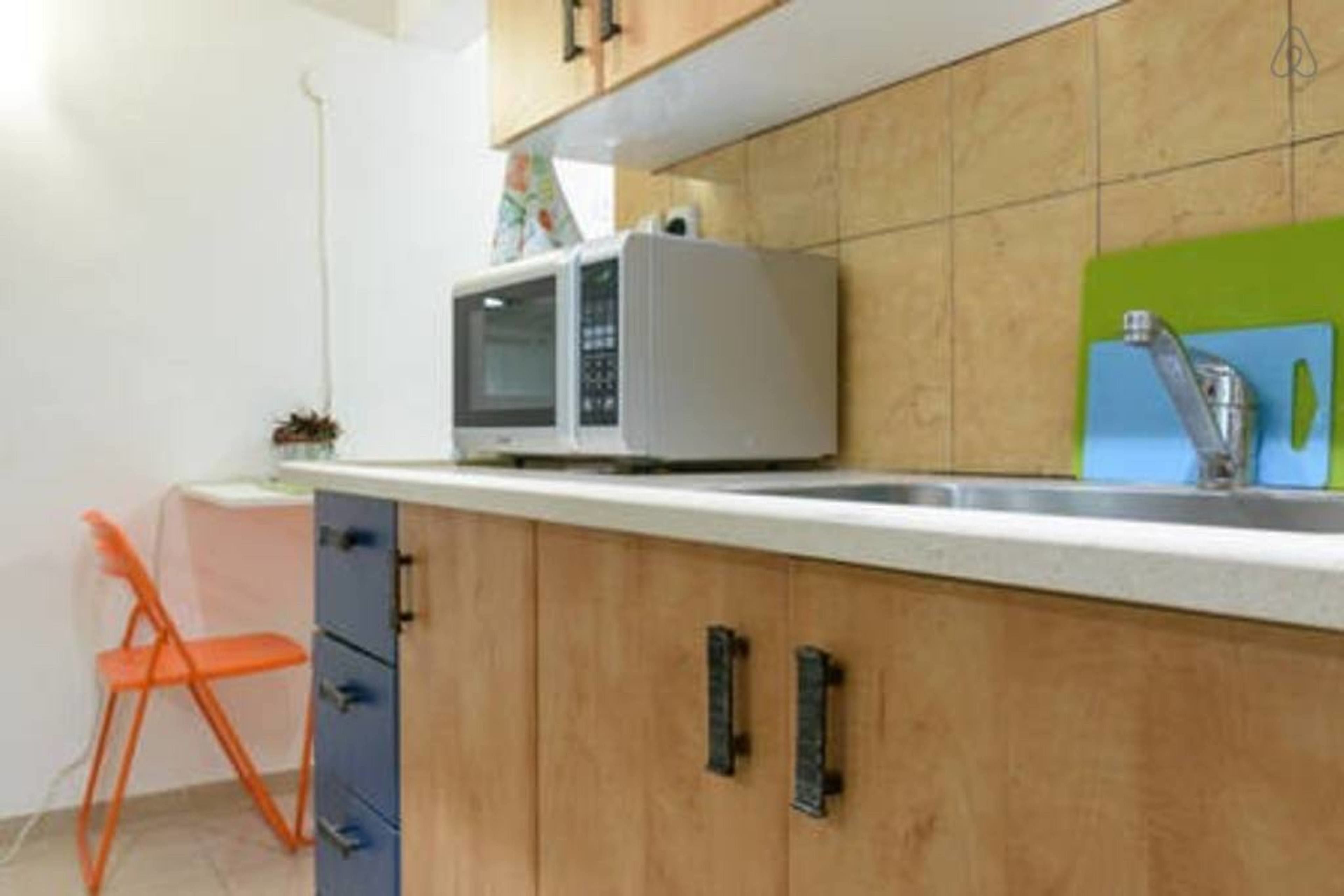 A kitchen with wooden cabinets, a microwave, and a green backsplash.