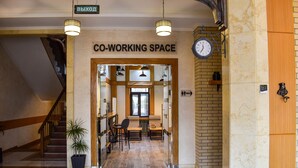 A co-working space with a staircase, a potted plant, and a clock on the wall. - Sacvoyage Hotel (Almaty)