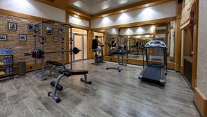 A gym with exercise equipment, a mirror, and a wooden floor. - Sacvoyage Hotel (Almaty)
