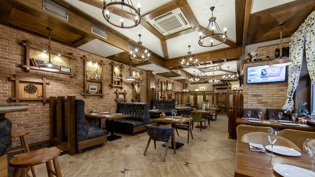 A restaurant with brick walls, wooden beams, and multiple dining areas with tables and chairs. - Sacvoyage Hotel (Almaty)