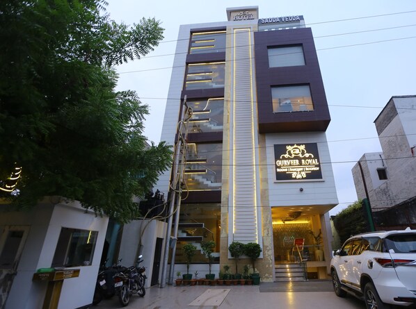 Ein modernes Hotel mit einem Schild mit der Aufschrift 'Gurveer Royal' und 'Sadda Veddy' an der Fassade.