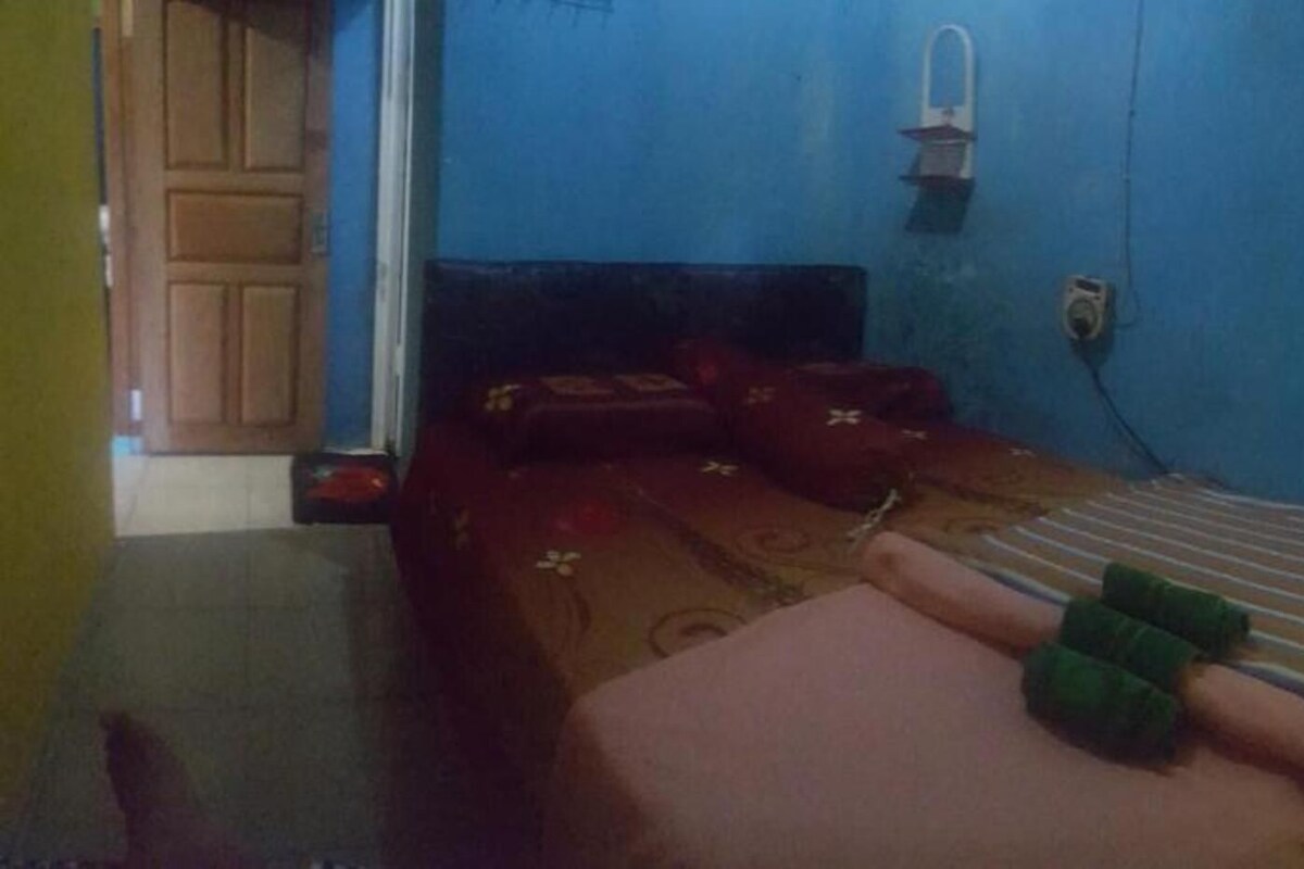 A narrow room with a bed, a small table, and a wall-mounted heater.