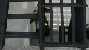 A staircase with a black railing leading to a landing with a window. - Patchy&PPraw Family (Ubon Ratchathani)