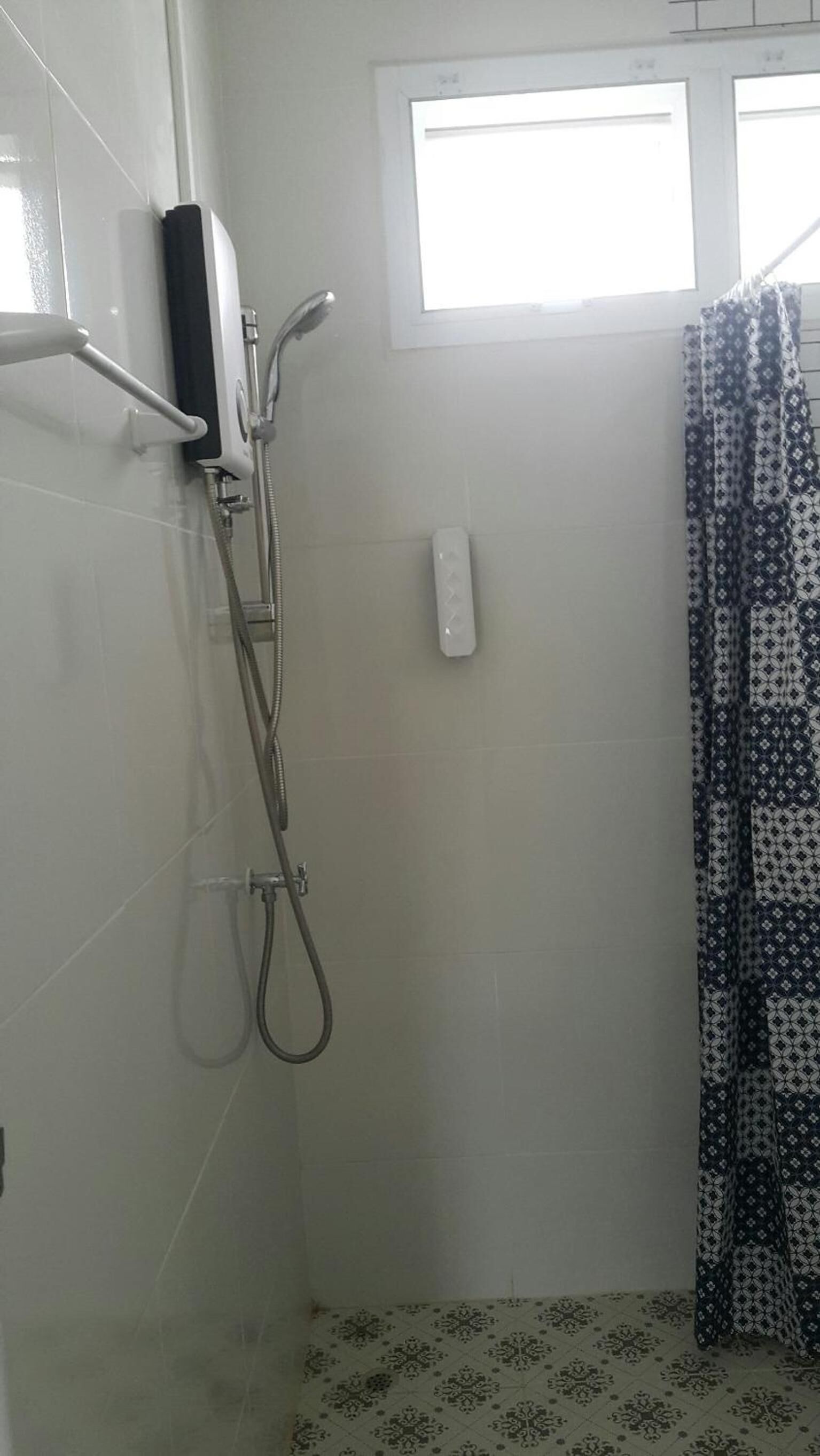 A shower area with a handheld showerhead, a wall-mounted faucet, and a control panel.
