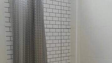 A bathroom with a toilet, a shower curtain, and patterned tiles on the walls.