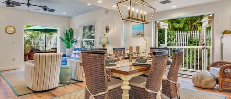 A dining area with a wooden table, wicker chairs, and a ceiling fan.