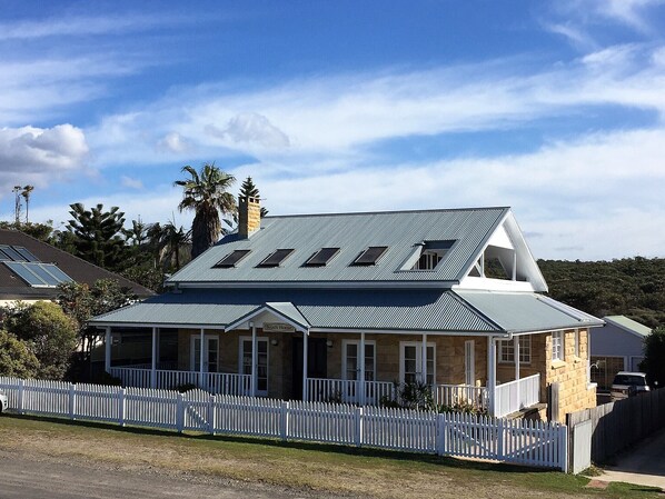A two-story house with a sloped roof, multiple skylights, and a white picket fence.