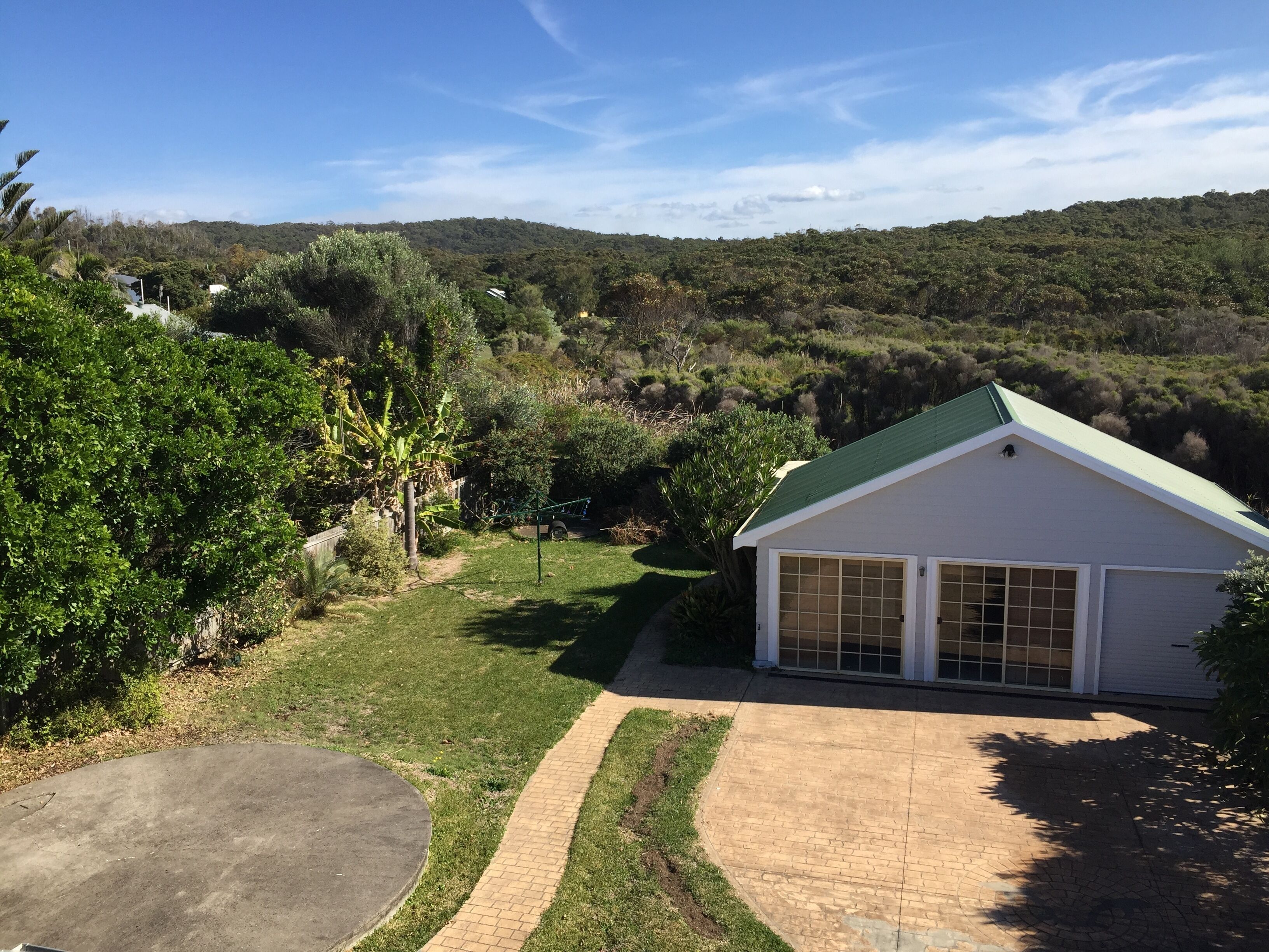 A house with a green roof, a garage, and a paved driveway.