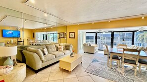 A modern living room with a sofa, coffee table, and a dining area with chairs and a table. - Love to Boat, Kayak or Canoe? Then this Mariner Pointe waterfront condo is for you!  Bring Your Boat! (Sanibel)