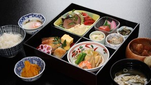 Eine traditionelle japanische Bento-Box mit verschiedenen Speisen, darunter Reis, Fisch, Gemüse und eingelegten Zutaten.