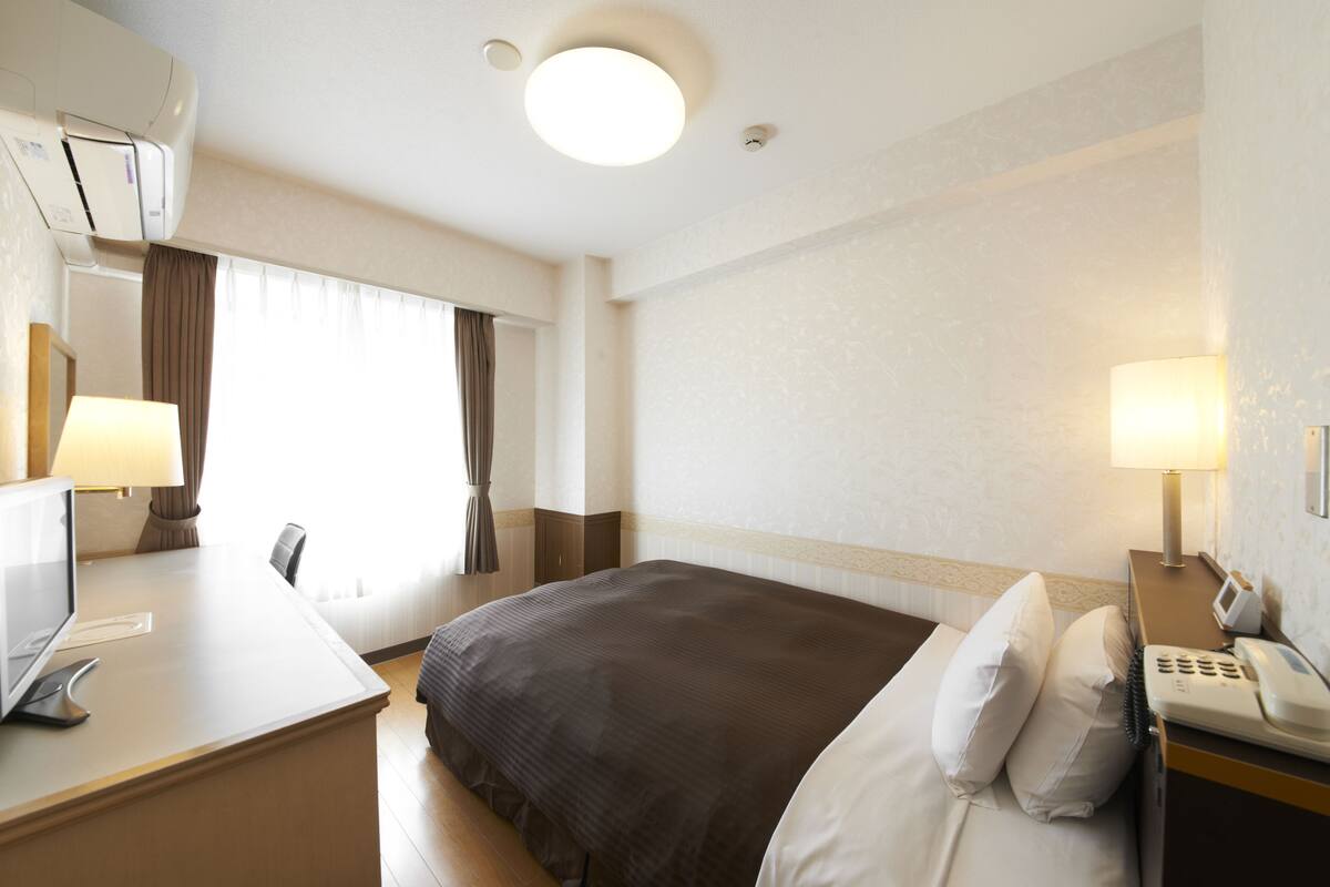 Habitación de hotel con cama, escritorio y teléfono.