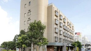 Ein modernes Hotel mit gebogener Fassade, zahlreichen Fenstern und einem überdachten Eingang.