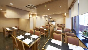 Ein Restaurant mit Sitzecken und Tischen, einer Theke und Blick ins Freie.