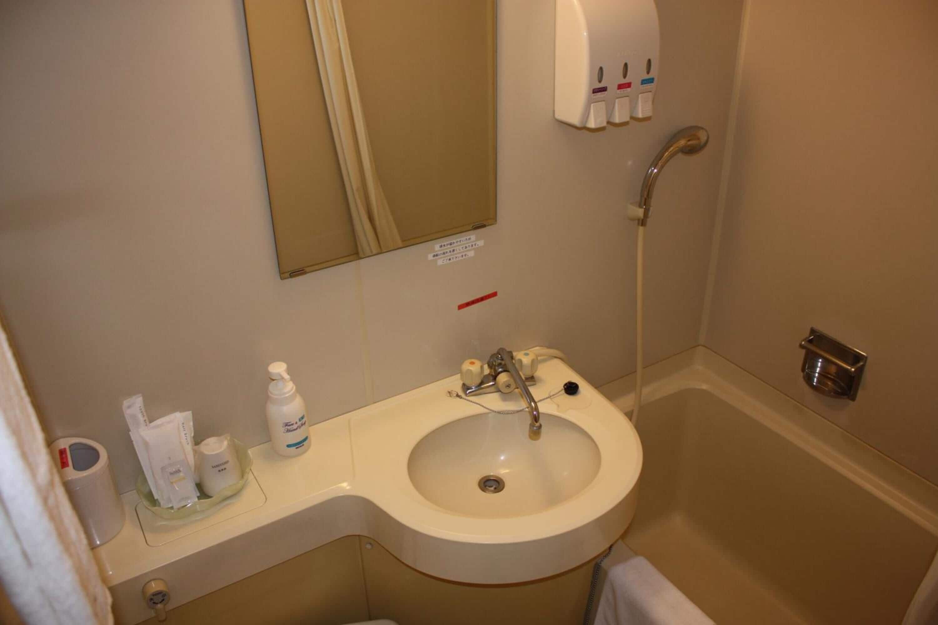 A bathroom with a sink, mirror, and hand dryer.