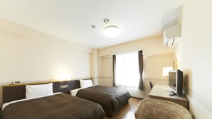 Ein Hotelzimmer mit zwei Betten, einem Schreibtisch, einem Fernseher, einem Sessel und einem Fenster mit Vorhängen.