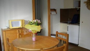 A small dining area with a wooden table, chairs, a microwave, and a bouquet of flowers. - Quiet rental with view of Mont Blanc - 4 people  (Saint-Gervais-Les-Bains)