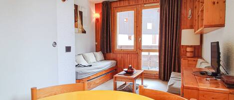 A cozy room with a bed, a desk, a chair, and a table with a book.