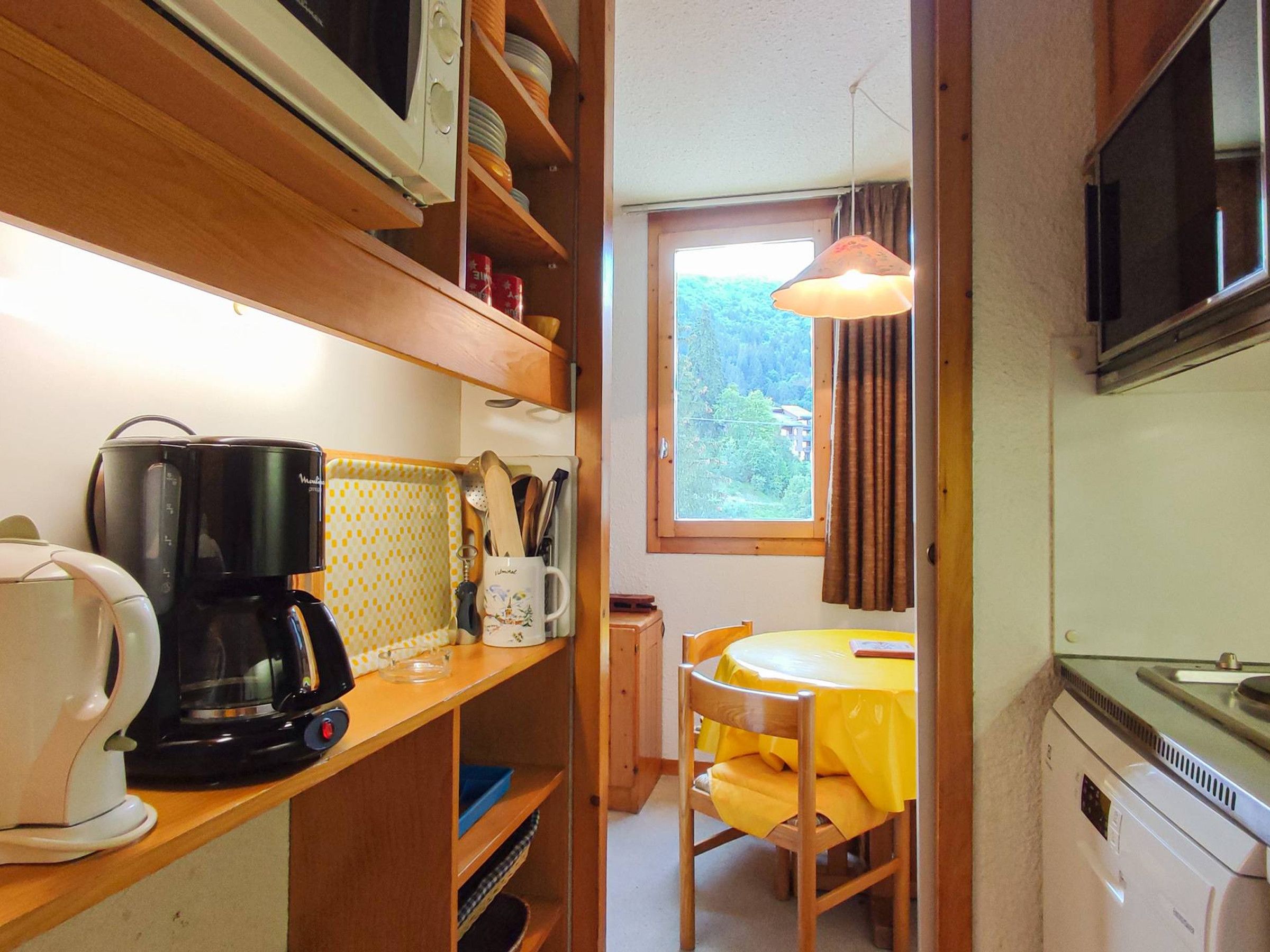 A compact kitchen with a coffee maker, microwave, and a dining area with a table and chair.