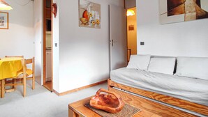 Une pièce comprenant un canapé, une table à manger avec des chaises, un coin cuisine et un tableau au mur.