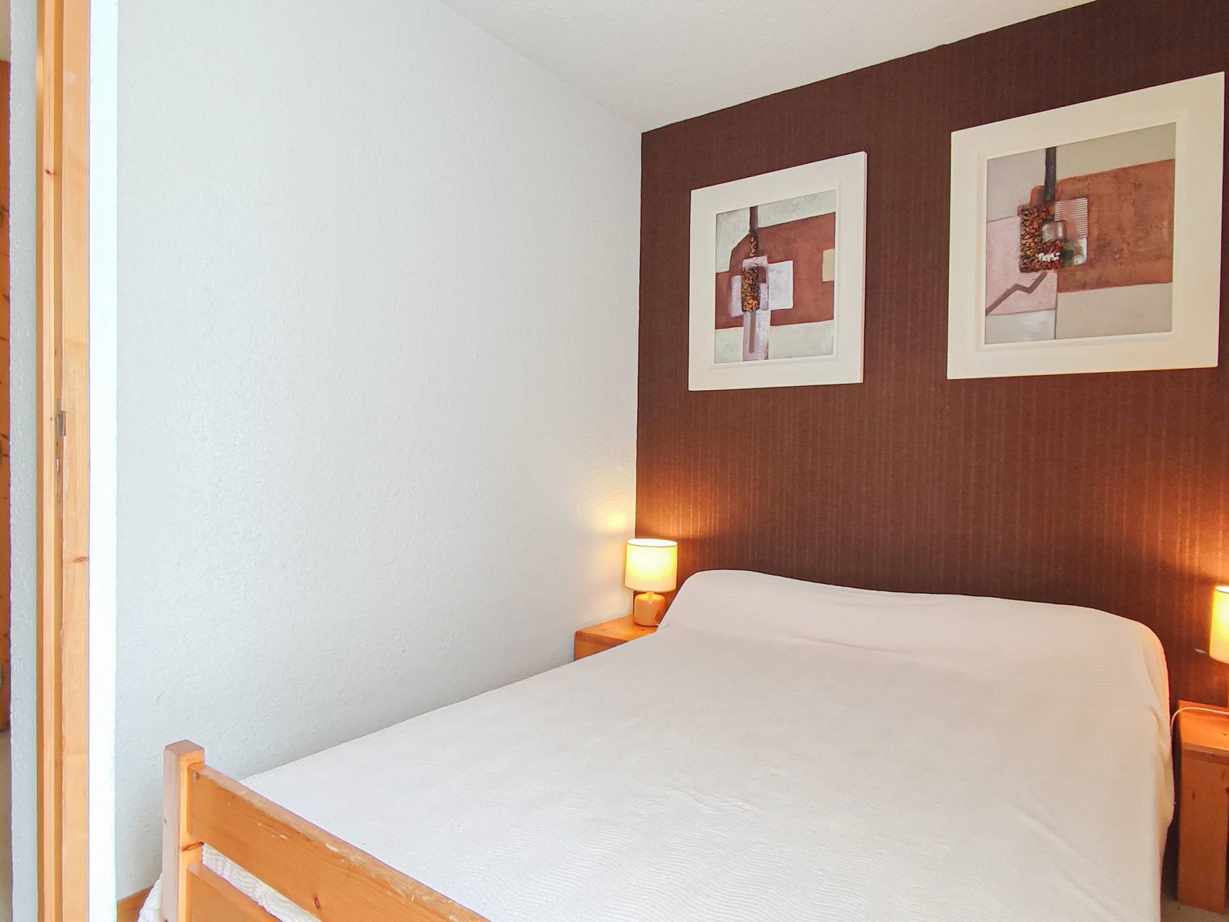 Ein Hotelzimmer mit einem Bett, zwei Wandleuchten und zwei gerahmten Kunstwerken.