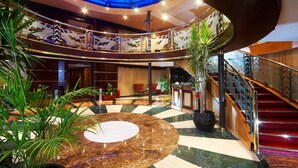 A grand lobby with a central marble fountain, a glass-domed ceiling, and a staircase with red carpet. - Nile Carnival Cruise (Luxor)